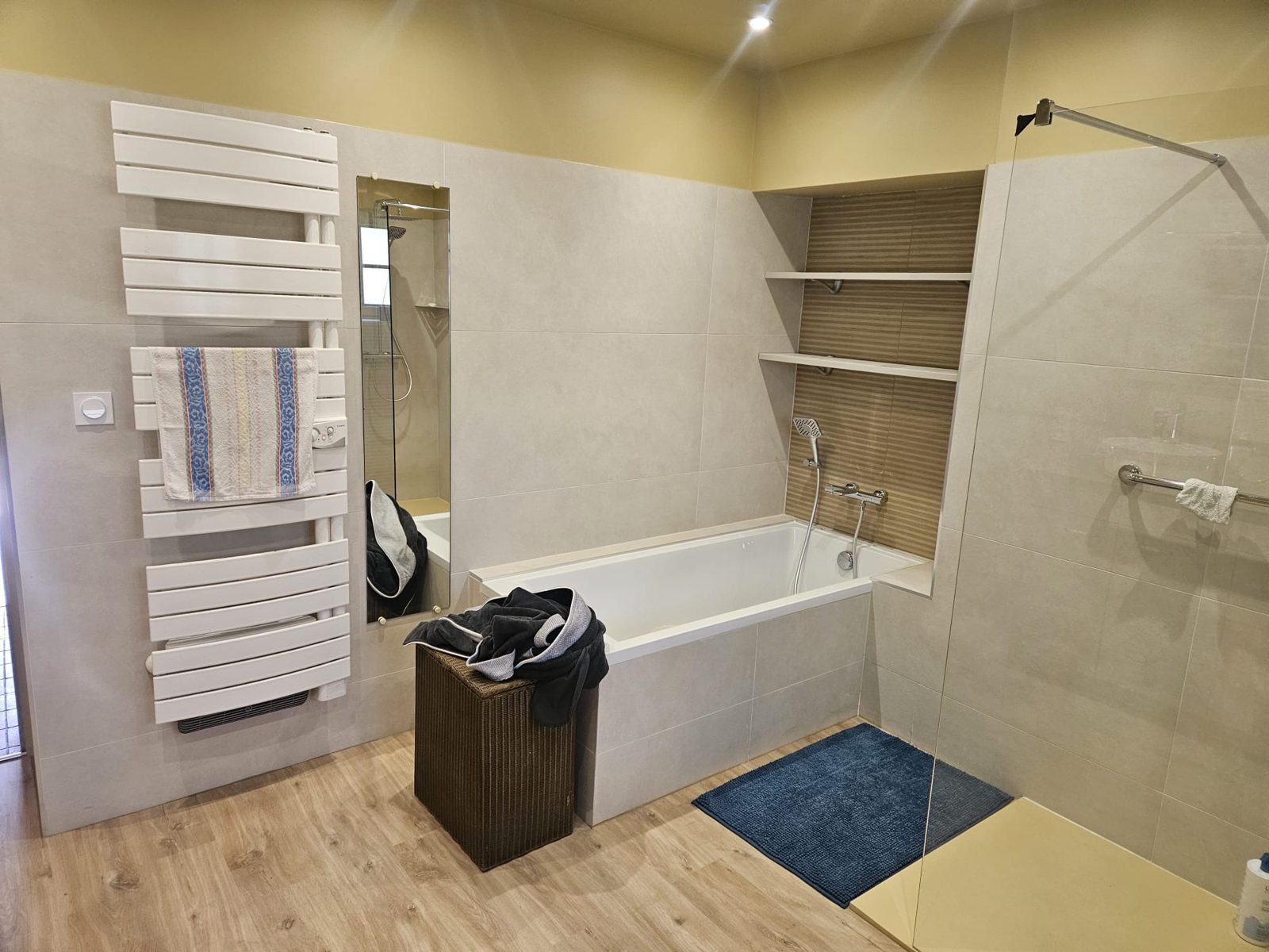 Baignoire encastrée avec tablier carrelé, niche en faïence décorative et étagères, sèche-serviettes blanc