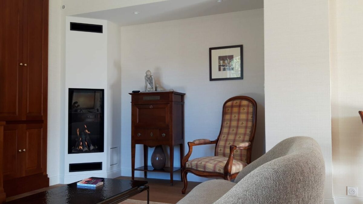 Cheminée moderne avec foyer fermé vertical intégré dans un habillage blanc, salon rénové à Rennes