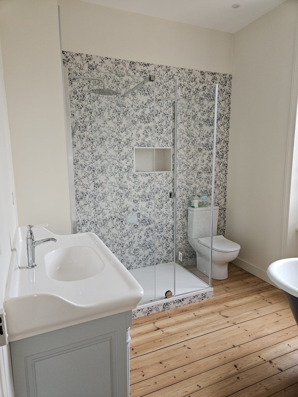 Douche avec carrelage à motif floral bleu, niche murale et paroi vitrée dans une salle de bain rénovée