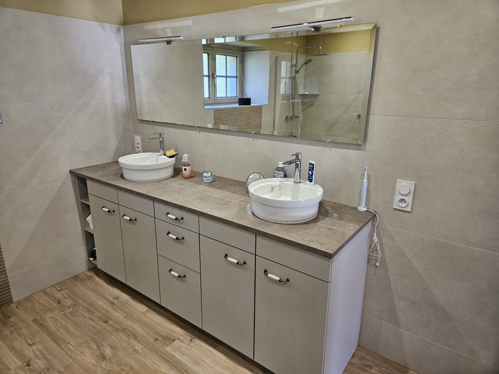 Grand meuble double vasque avec vasques à poser, miroir éclairé et carrelage grand format dans une salle de bain à Rennes