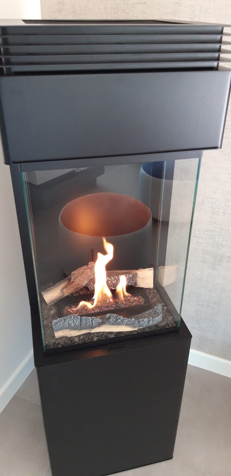 Flamme d'un poêle à éthanol avec vitre sur trois faces et fausses bûches décoratives