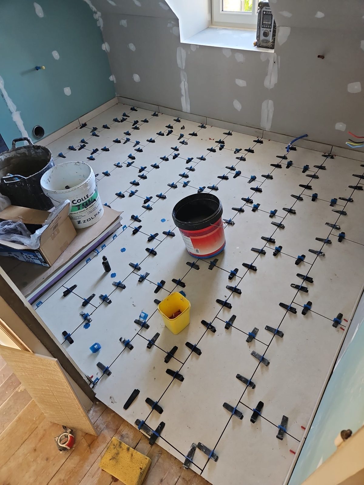 Pose de carrelage au sol grand format pendant la rénovation d'une salle de bain