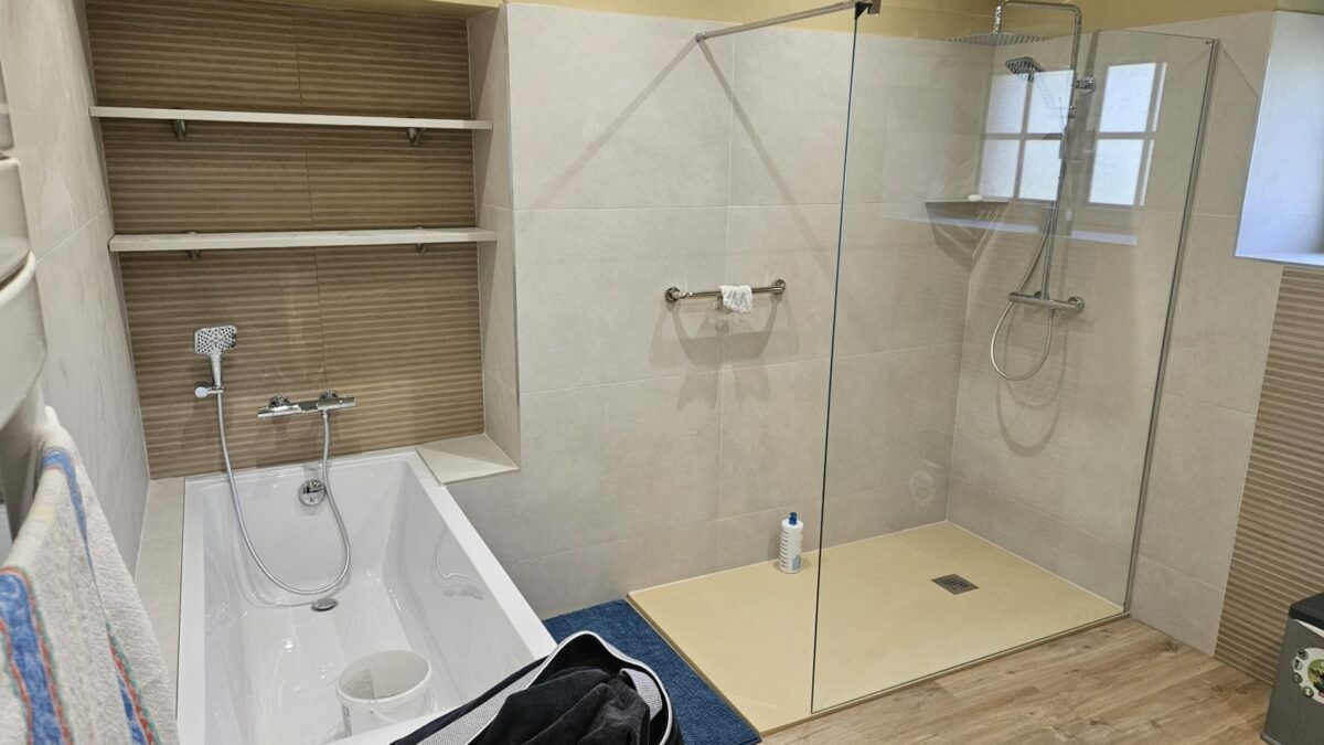 Salle de bain rénovée à Rennes avec baignoire encastrée, niche à étagères et douche avec paroi vitrée