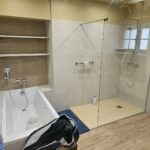 Salle de bain rénovée à Rennes avec baignoire encastrée, niche à étagères et douche avec paroi vitrée