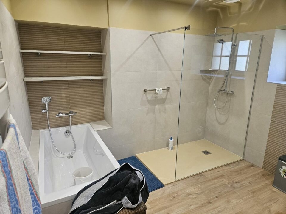 Salle de bain rénovée à Rennes avec baignoire encastrée, niche à étagères et douche avec paroi vitrée